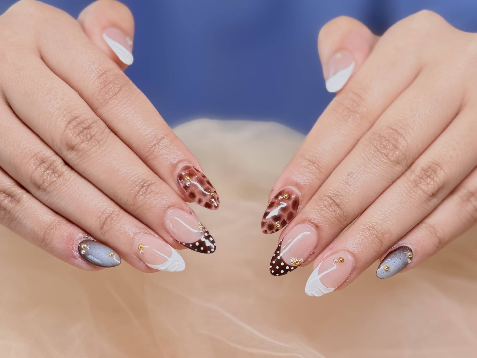 Tortoiseshell and polka-dot French tips on almond nails over blush tulle